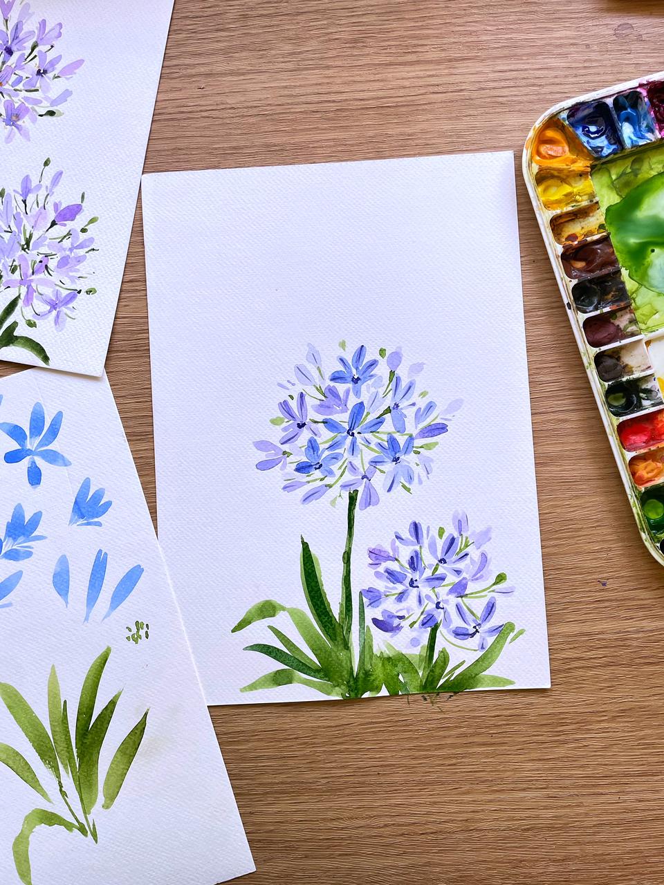 Blue agapanthus watercolor painting beside a palette